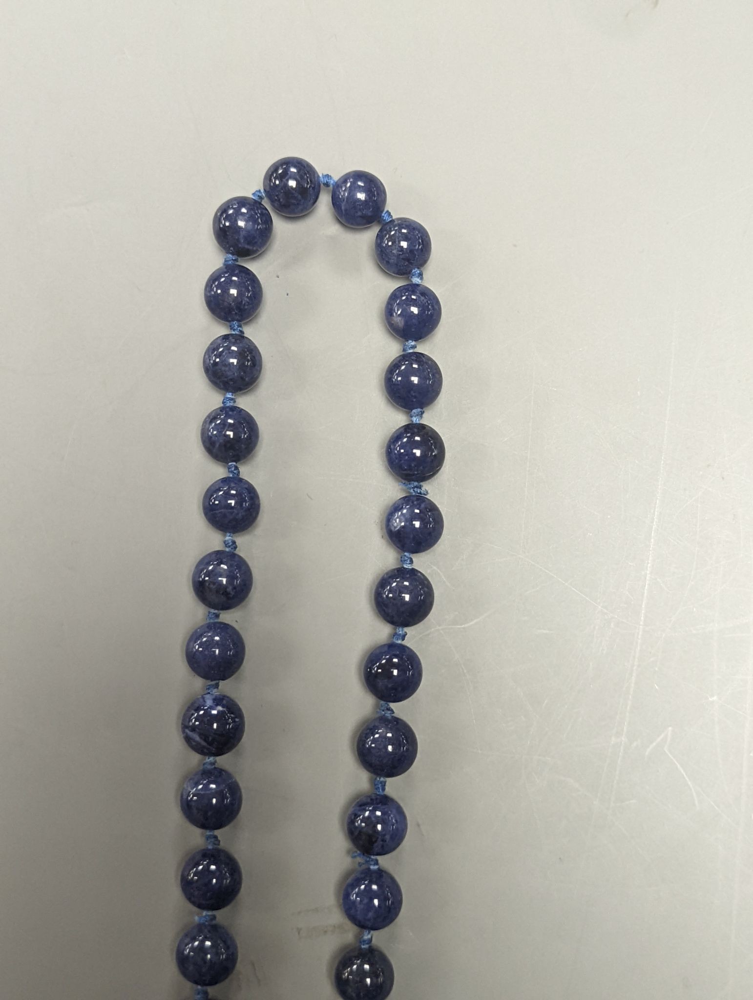 A yellow metal and six stone emerald cut amethyst set part bracelet(a.f.), 17.1cm and a modern single strand lapis lazuli bead necklace with 14k yellow metal clasp.